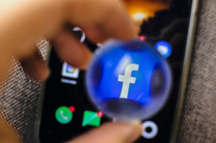 El logo de Facebook es visto en la pantalla de un teléfono, distorsionado por una esfera de cristal.