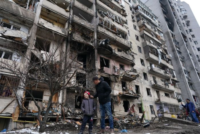 Dos personas caminan por el frontis de un edificio destruido en Kiev.