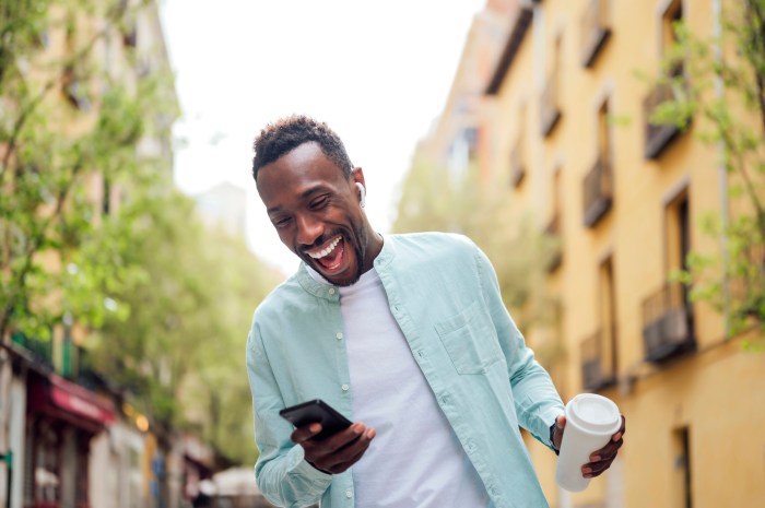 Hombre sonríe mientras mira la pantalla de su celular.