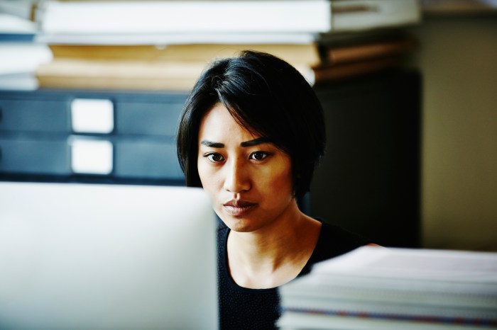 Una mujer joven con rasgos asiáticos observa la pantalla de una computadora.