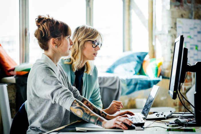 Dos mujeres trabajan frente a sus computadoras.