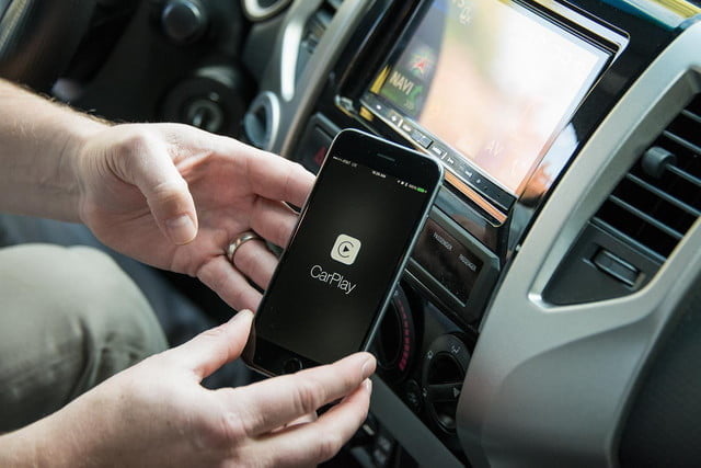 Un hombre dentro de un auto con un iPhone en la mano para configurar Car Play.