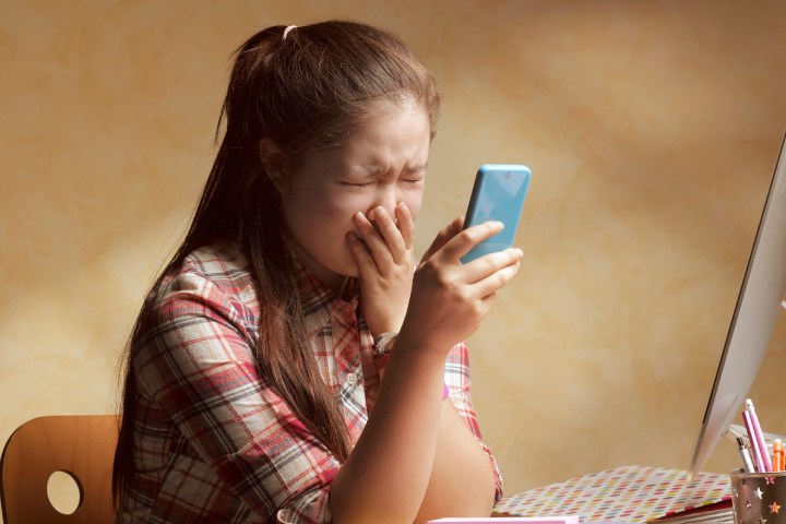 An Asian woman is crying while looking at her phone 