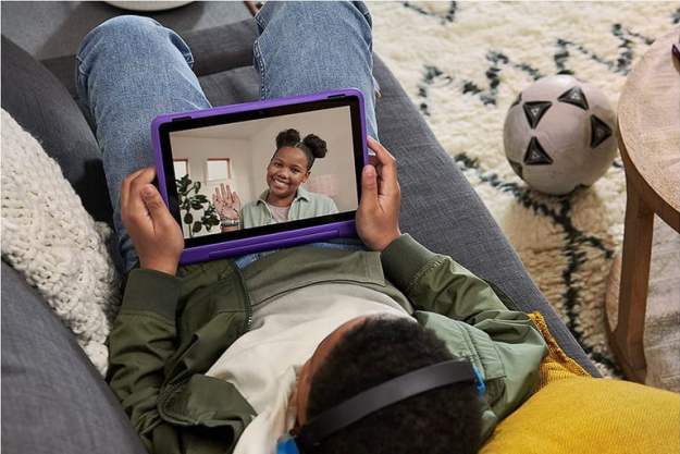 Un niño recostado en un sofá utiliza la Fire HD 10 Kids Pro para chatear por vídeo.