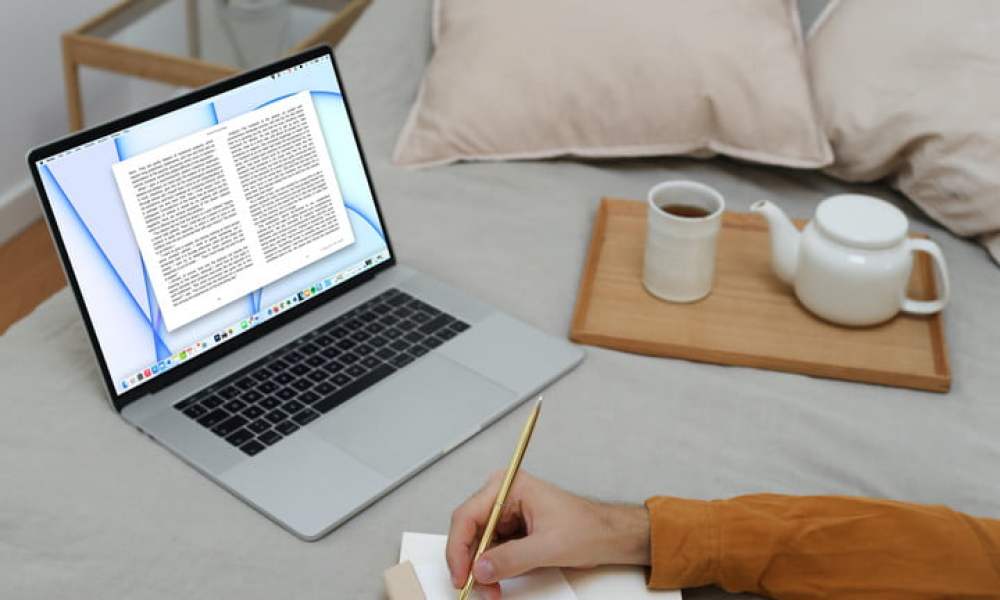 Una persona en la cama con la aplicación de Apple Books abierta en una MacBook.