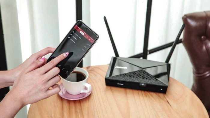 Un teléfono es sostenido por una mano junto a un router y una taza de café.
