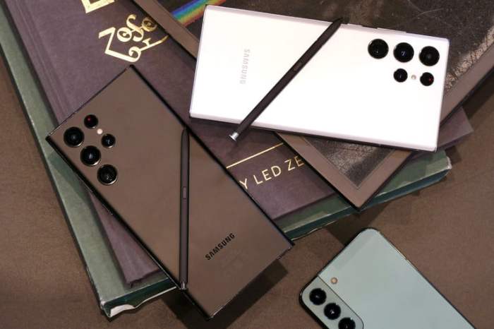 Dos teléfonos Galaxy S22 Ultra en blanco y negro sobre unos libros y un iPhone 13 Pro Max a un lado.