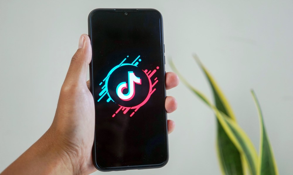 Una mano sostiene un teléfono donde aparece el logo de la red social TikTok.