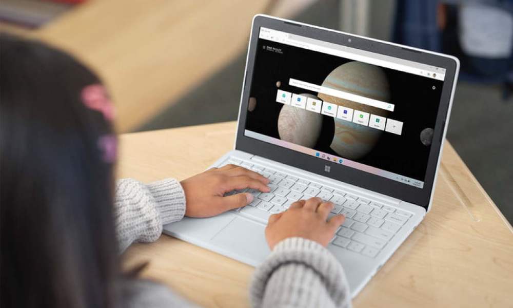 Una niña trabajando con una Chromebook en color blanco sobre una mesita.