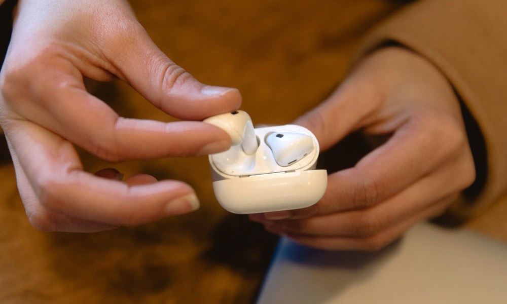 Un AirPod es sacado de sus estuche por las manos de una mujer.