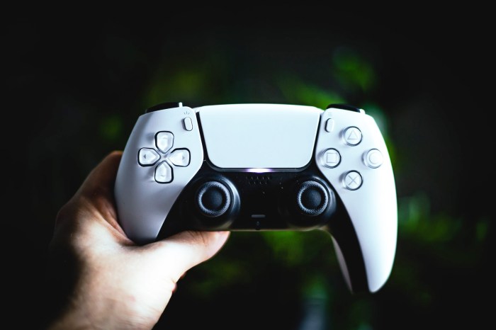 Una mano sostiene un control de PlayStation 5 blanco.