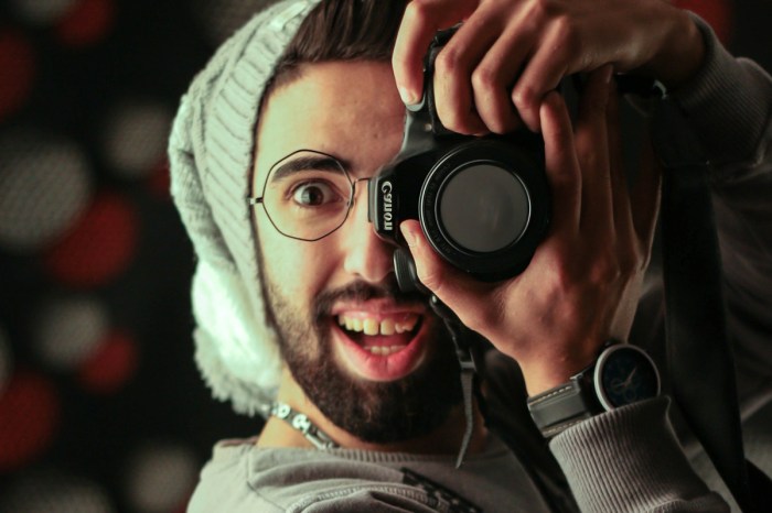 Un hombre apunta a la cámara con una cámara DSLR Canon.