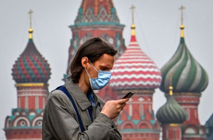 Un hombre con mascarilla revisa su celular en Moscú.