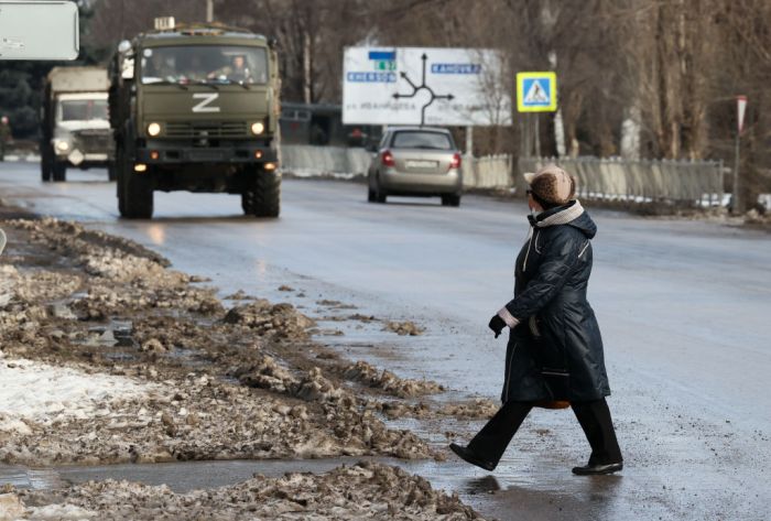 Un hombre atraviesa una calle frente al avance de un camión militar.