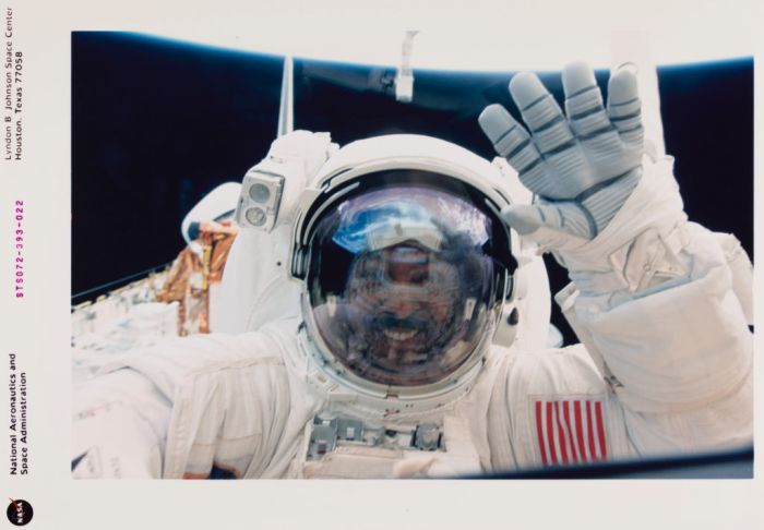 Un astronauta saluda a la cámara durante una caminata en el espacio.