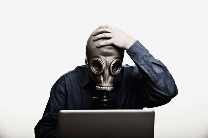 Un hombre usa una máscara de gas mientras está frente a su computadora.