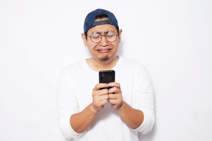 Un hombre con anteojos y gorra llora mientras reciba su teléfono