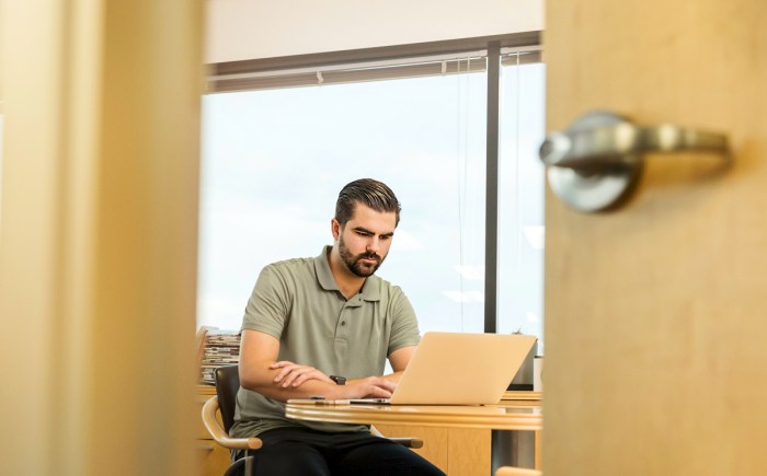 Un hombre trabaja en una laptop dentro de una oficina.