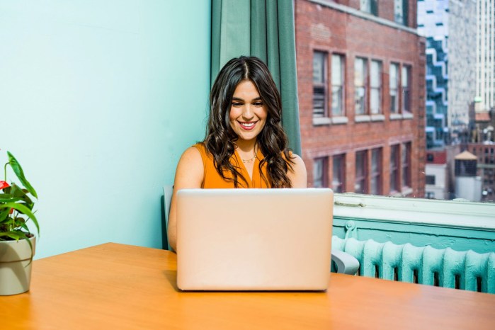 Una mujer trabaja con una laptop en una oficina de tonos azul claro.