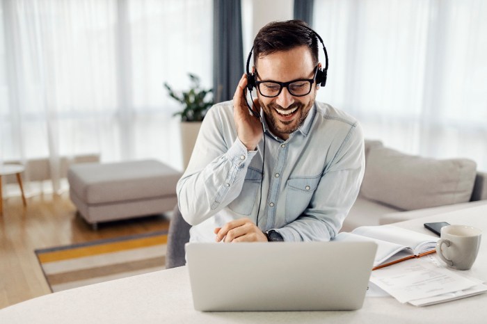 Un hombre joven con barba y lentes contesta una llamada en su computadora