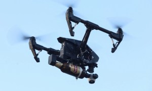 un dron vuela con una bomba molotov adosado en sus brazos