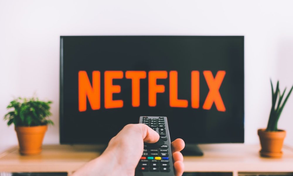 Una persona apunta con el control remoto a su televisor con el logo de Netflix.