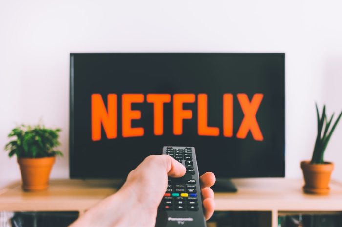 Una persona apunta con el control remoto a su televisor con el logo de Netflix.