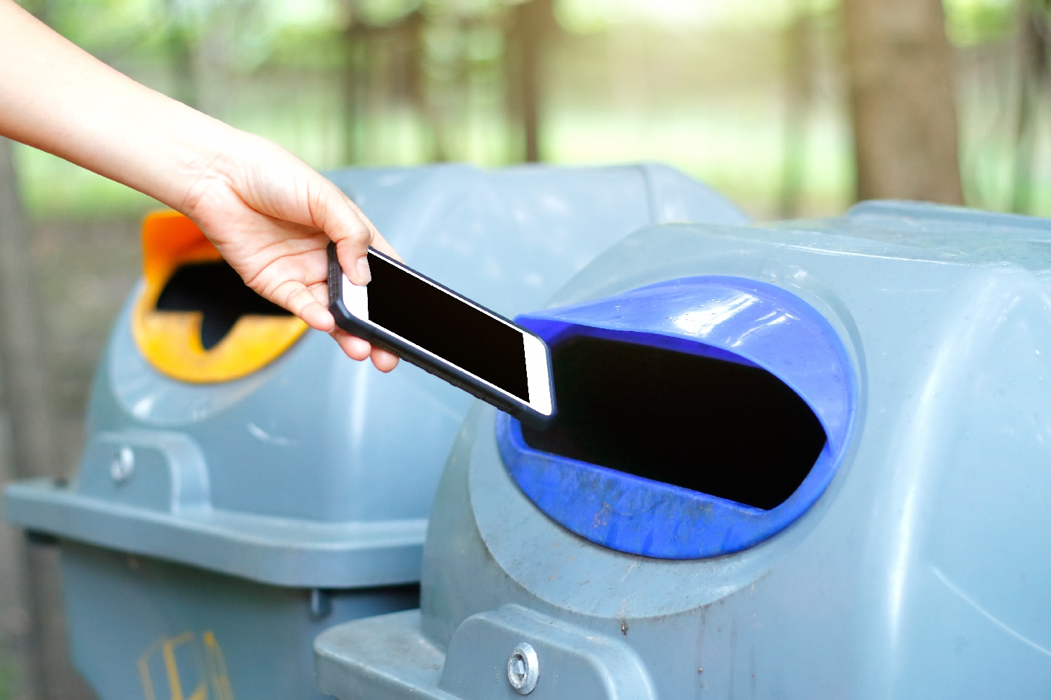 Una persona deposita un teléfono en un buzón de reciclaje