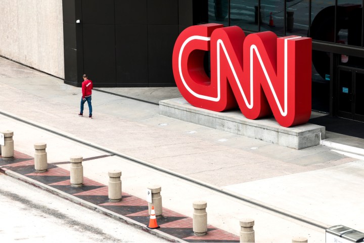 A man walks in front of the giant CNN logo