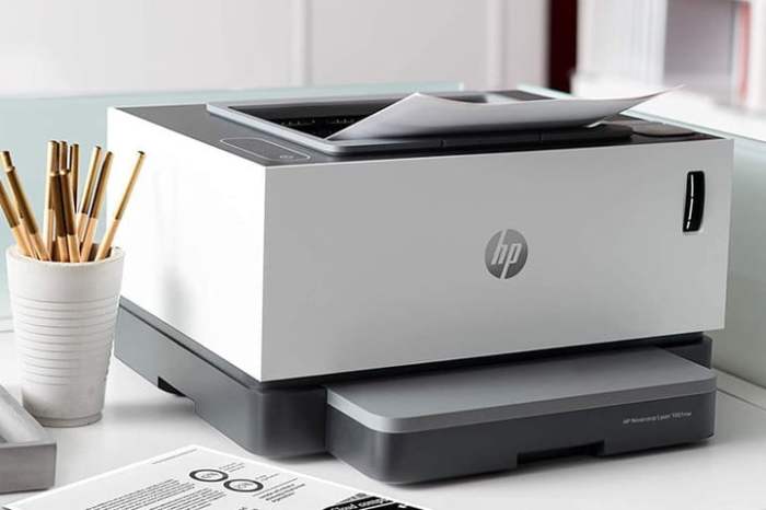 Impresora HP Neverstop Laser 1001nw sobre una mesa junto a unos accesorios.
