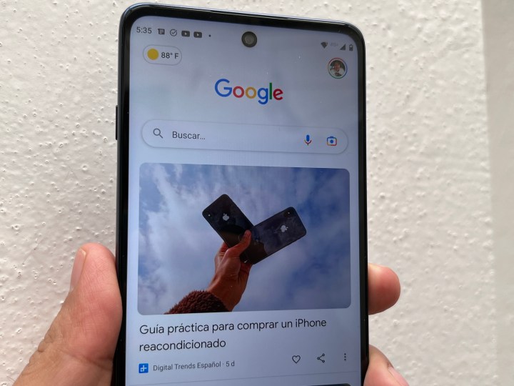 Usuarios sosteniendo un celular que muestra la interfaz principal de Google Discover.