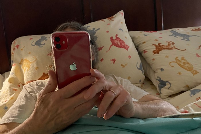 Una persona observa la pantalla de su iPhone mientras se encuentra acostada en la cama antes de dormir.