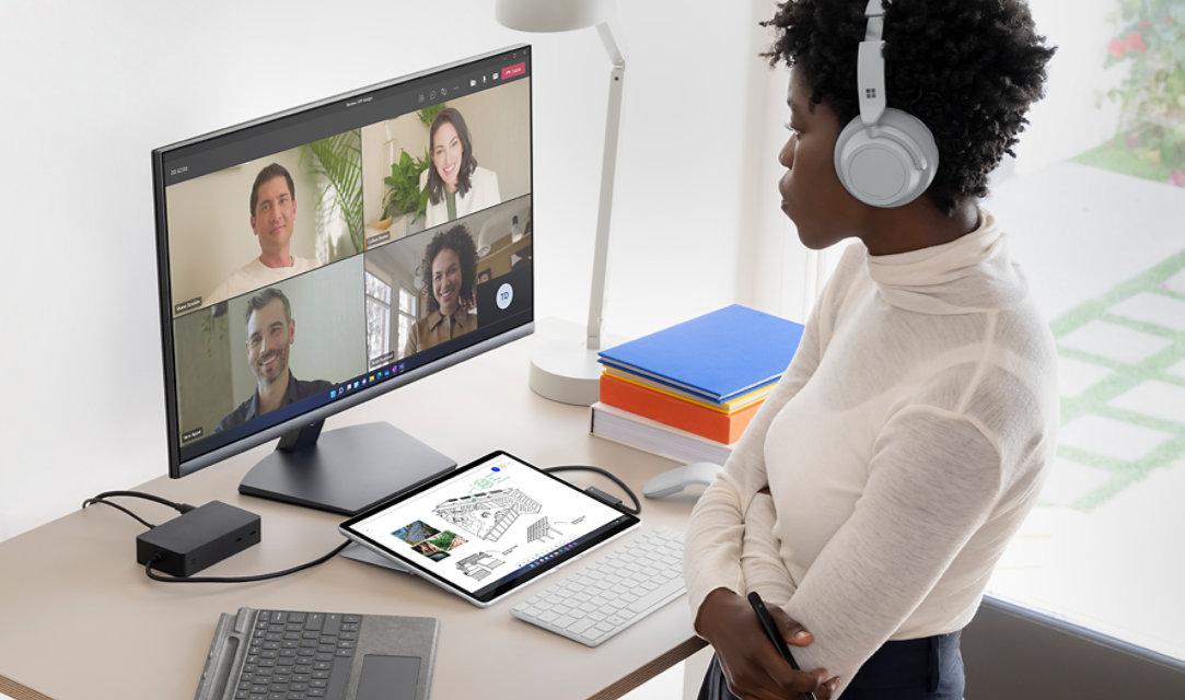 Una mujer con audifonos frente a una computadora.