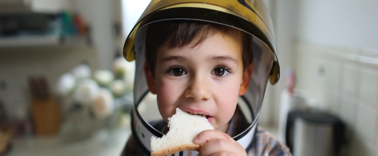 por que astronautas no pueden comer pan espacio a four year old boy wearing cosmonaut helmet  eating sliced bread in the kitc