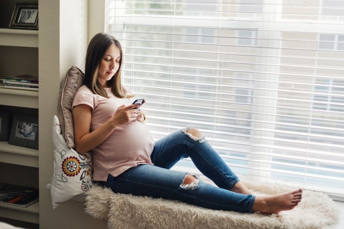 aplicaciones embarazos periodos falta privacidad smiling pregnant woman using her smartphone at home
