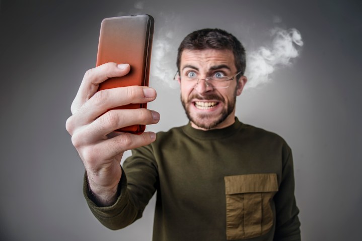 Hombre enojado echando humos con su celular – Cómo bloquear un número desde cualquier teléfono.