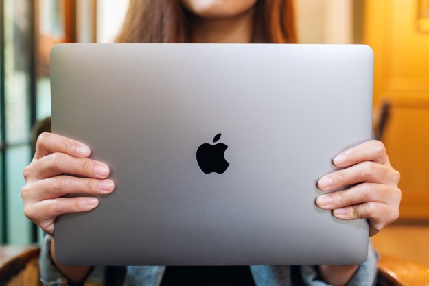 Mujer sosteniendo una MacBook Pro y mostrando el logo de Apple – Cómo limpiar o restaurar de fábrica una Mac en unos pocos pasos.