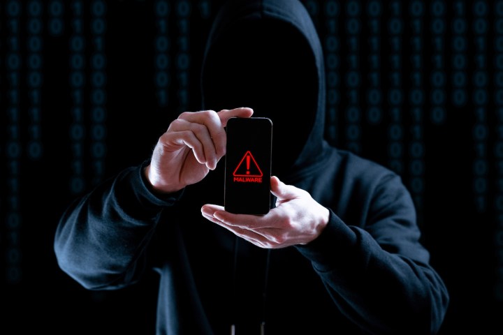 Pirata informático mostrando un celular hackeado.