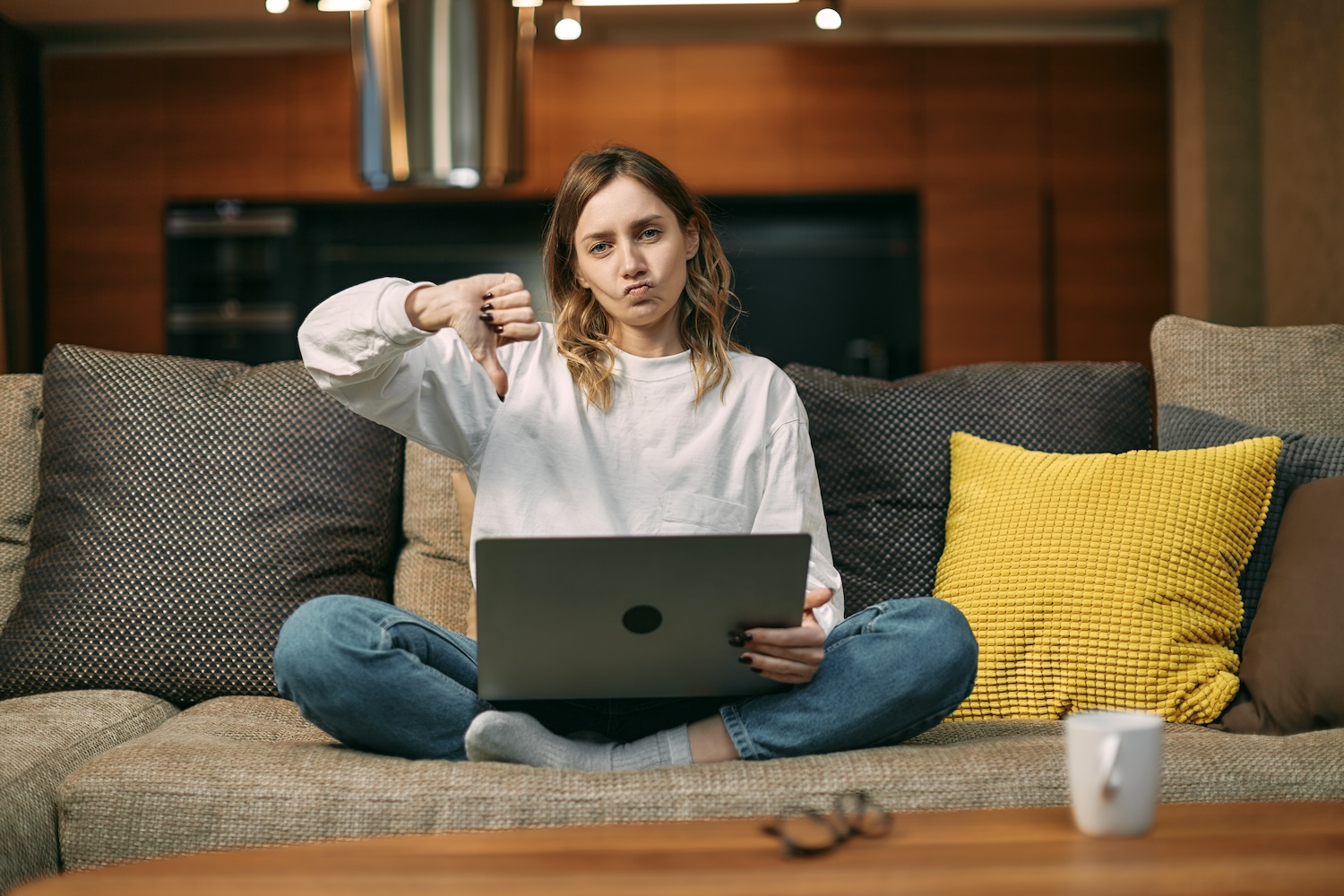 Mujer joven con una laptop y haciendo el pulgar hacia abajo – Cómo desinstalar Windows 11