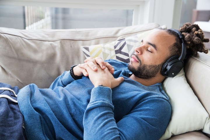 Hombre recostado en un sofá escuchando música.