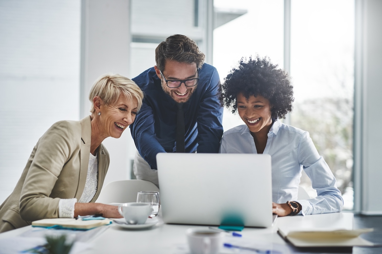 Tres personas felices frente a la pantalla de un ordenador– Cómo grabar la pantalla de tu computador.