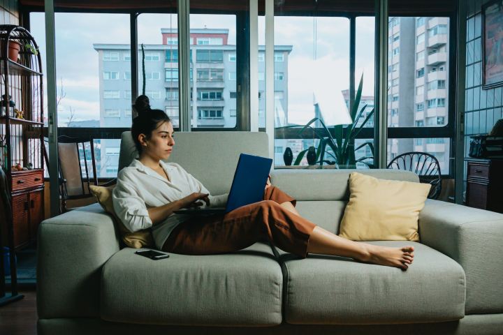 Mujer sentada en el sofá mientras mira el laptop