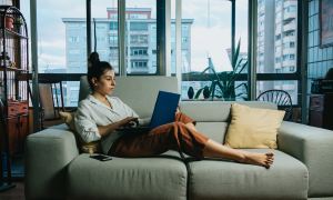 Mujer sentada en el sofá mientras mira el laptop