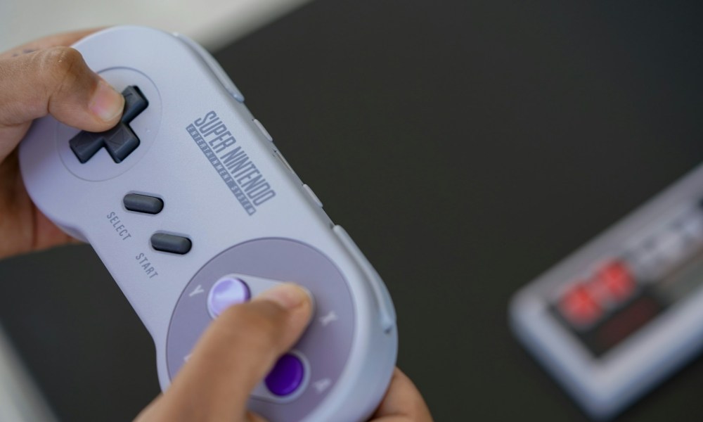 Unas manos sosteniendo un control de Super Nintendo (SNES).