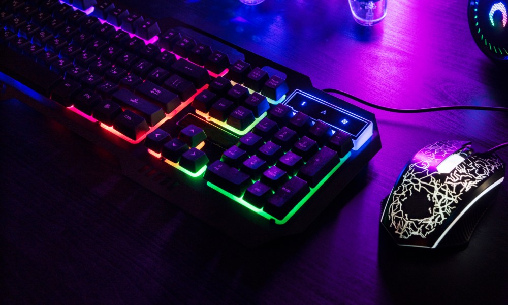 Un teclado y mouse con luces sobre un escritorio.