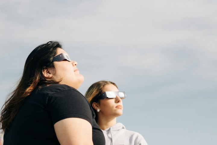 Personas viendo un eclipse solar con las gafas adecuadas para proteger la vista.